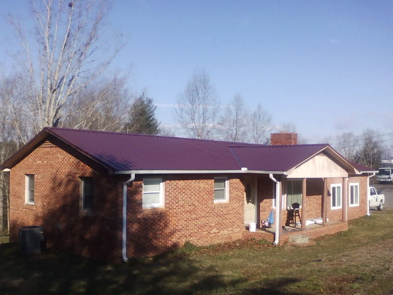 Burgundy metal roof on a brick ranch home with a new addition in Colstrip