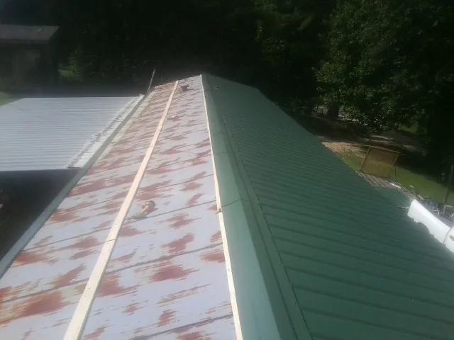 Old rusted panels beside newly installed green metal roofing — Wind Damage Roof Repair by Roofing Brothers in Colstrip