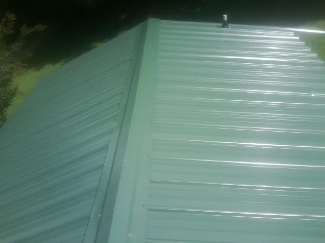New green metal panels meeting at the ridge of a roof — Flat Roof Repair work by our crew in Colstrip