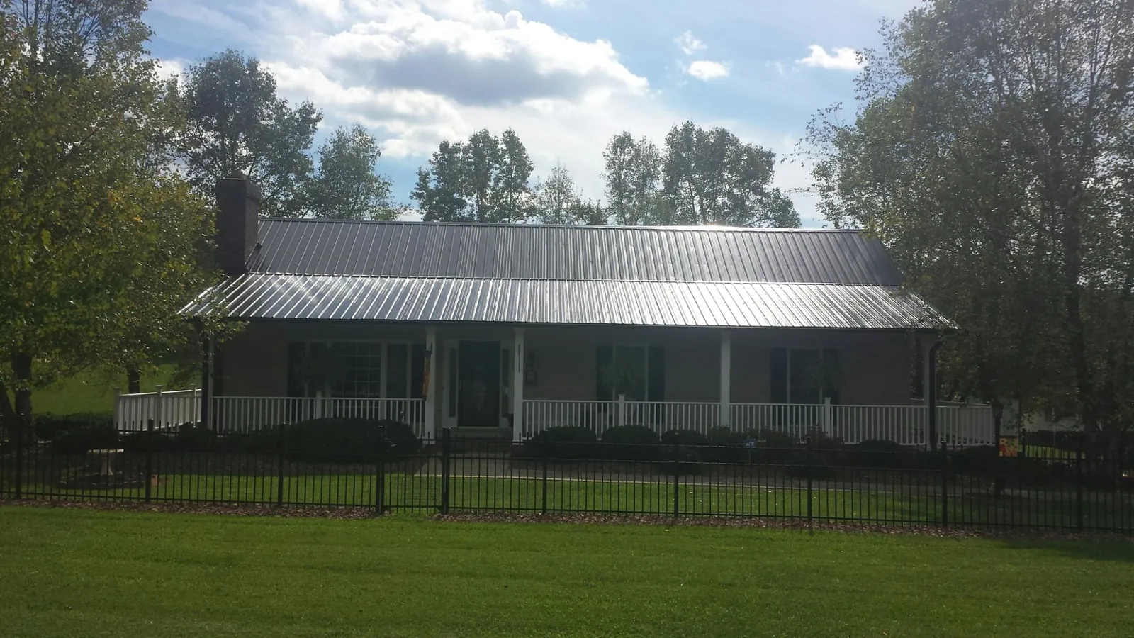 Gray metal roof on a brick ranch with a full width front porch — Gutter Guard Installation work by our crew in Colstrip