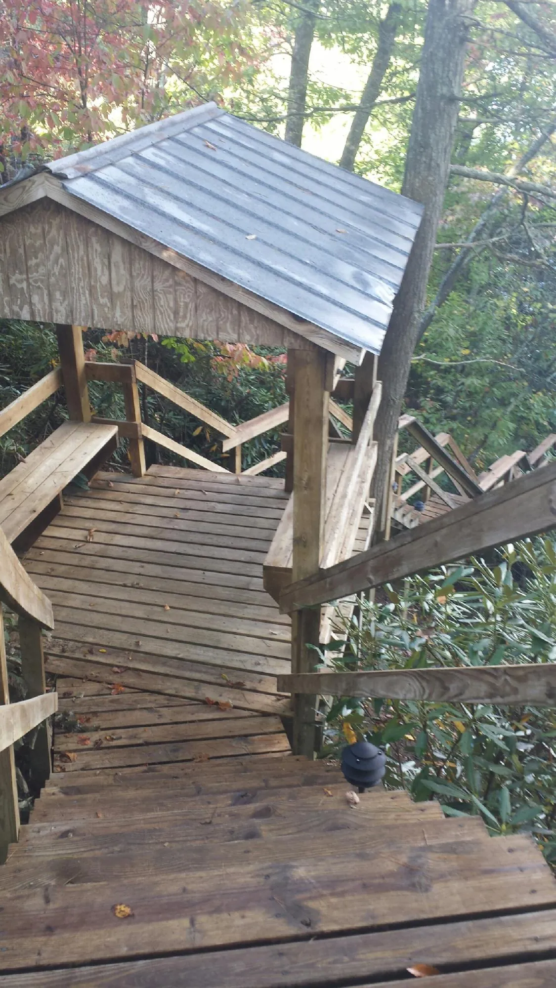Metal roofed shelter over wooden steps on a wooded walkway — Skylight Repair & Installation work by our crew in Colstrip