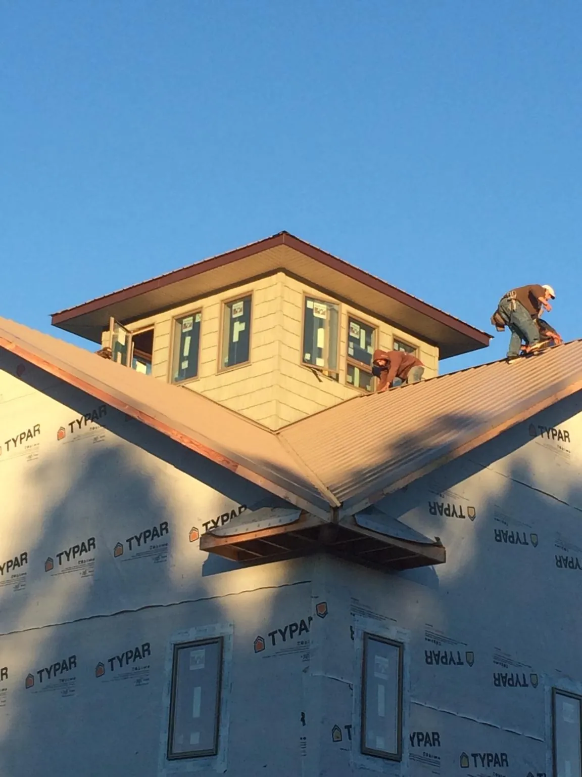 Roofers working around a rooftop cupola on a new metal roof at sunset — Roof Waterproofing in Colstrip by Roofing Brothers